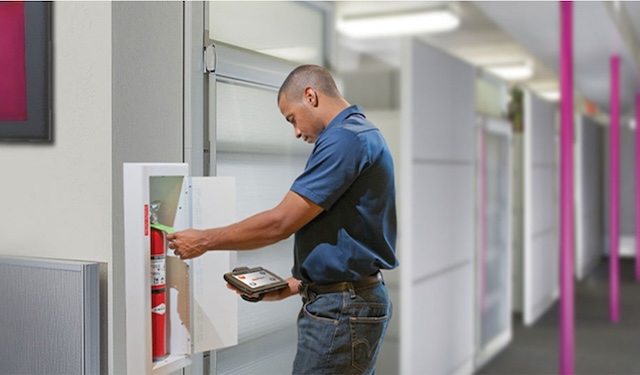 Technician inspecting a fire extinguisher using the MobiWork audit & inspection services software solution