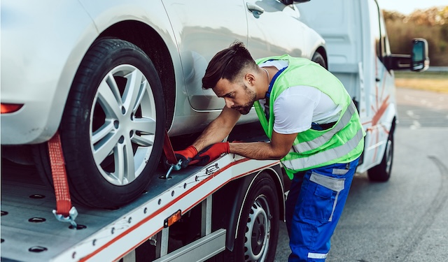 Technician performing emergency roadside services kneeling down to secure wheels using the MobiWork emergency roadside assistance services software solution