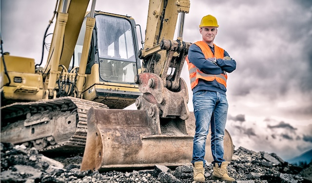 Construction worker standing in front of a crane using MobiWork equipment management services software