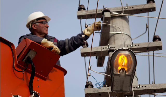 Lineman in crane working on a light pole using MobiWork utilities services software solution