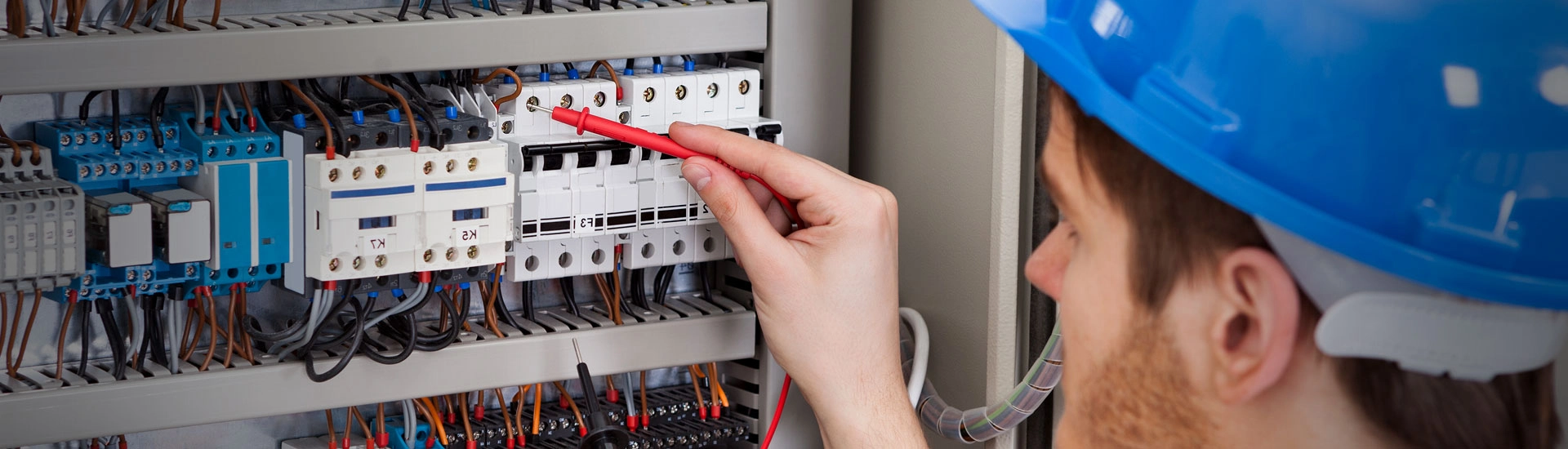 electrician who uses electrical contractor software works on lighting control panel
